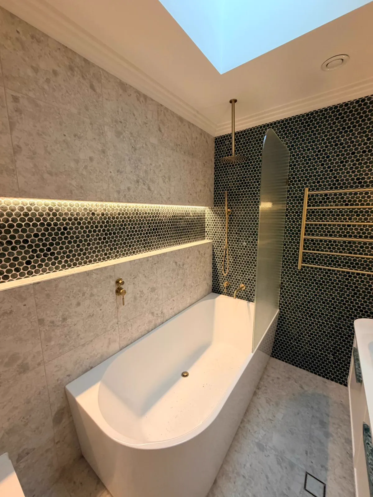 Modern bathroom with freestanding bath, brass tapware and green penny-round feature wall, Northern Beaches
