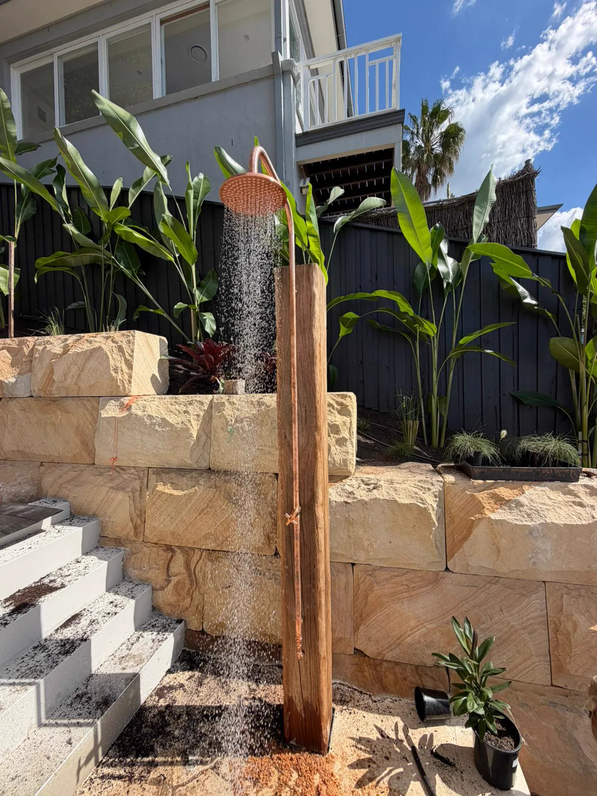 Copper outdoor shower plumbed against a sandstone retaining wall, Northern Beaches